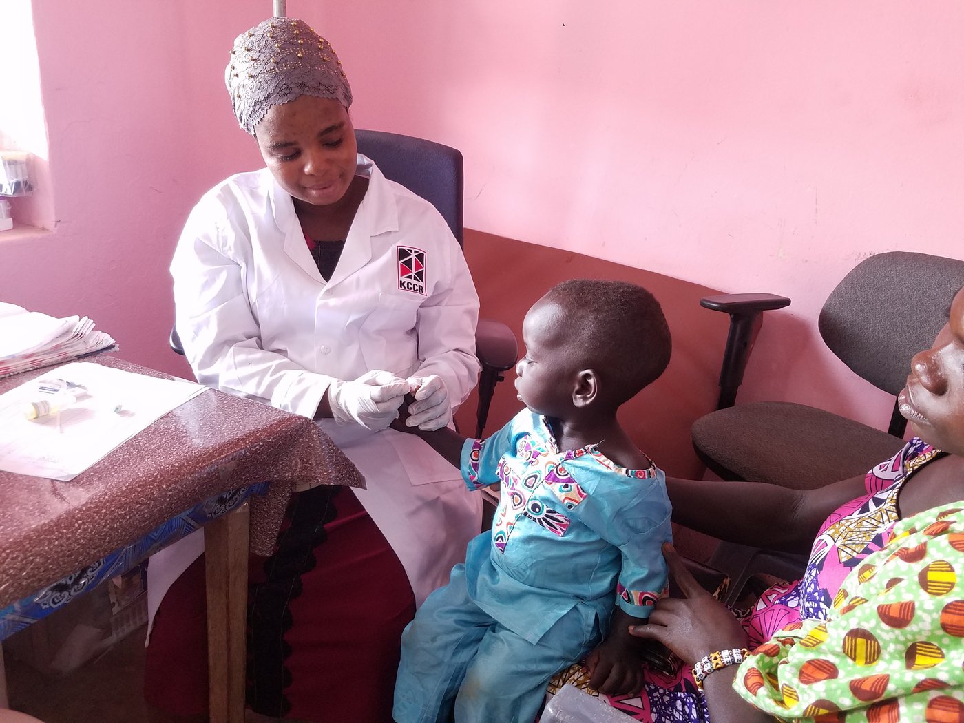 Das Bild zeigt eine afrikanische Ärztin bei der Bluentnahme bei einem Kleinkind zur Malaria-Diagnostik.