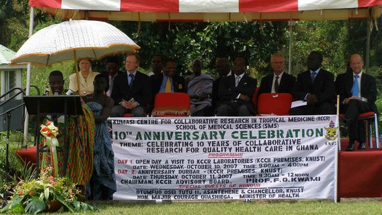A group sits on a stage, in the foreground a banner with 10th Anniversary