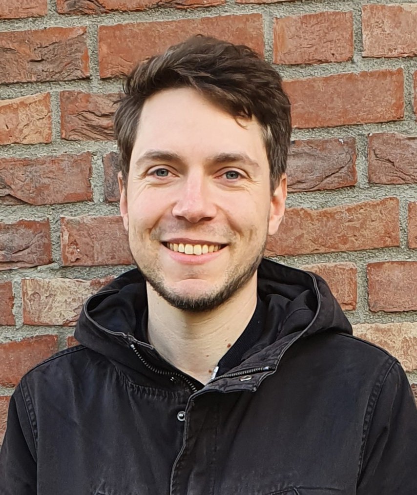 Dr Joachim Michael Matz: a researcher in front of a brick wall, wearing a hooded jacket, brown hair and a short chin beard.